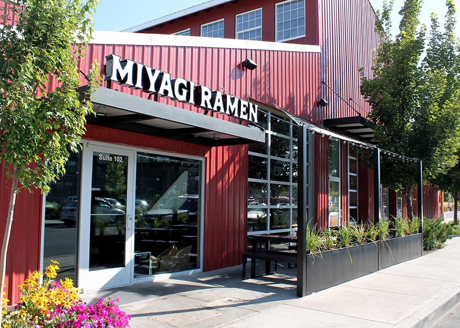 The red Box Factory storefront of Miyagi Ramen; the large white sign and the outdoor seats lined by box planter